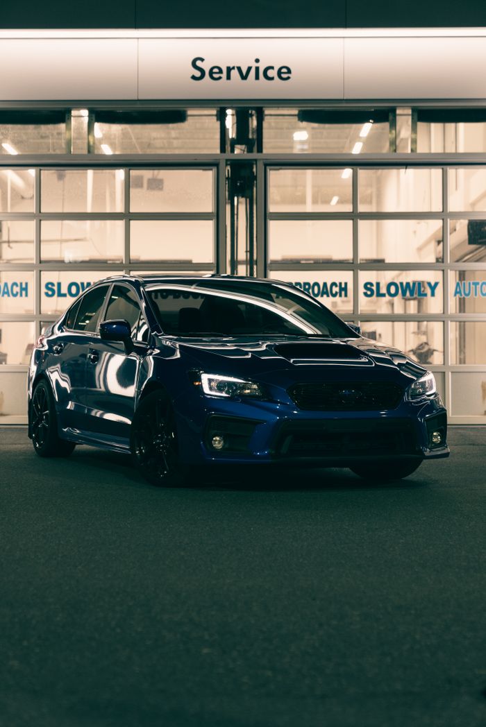 A modern blue car parked in an automotive service area at night, showcasing design and technology.